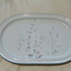 May include: A white oval serving platter with a floral design featuring green and brown leaves and pink flowers.