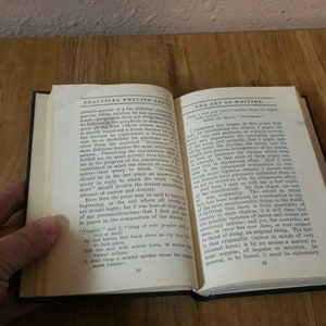 May include: An open book with the title "Practical English" on the left page and "The Art of Writing" on the right page. The book is open to page 22 and the text is visible on both pages.