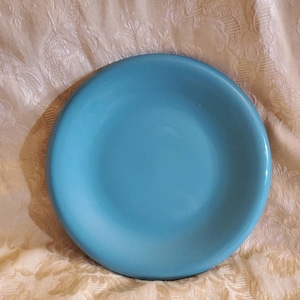 May include: A light blue ceramic plate with a smooth, slightly rounded rim.