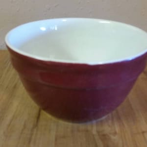 以下が含まれることがあります： 白い内側を持つ赤いセラミック製のミキシングボウル。ボウルは丸みを帯びた形をしていて、滑らかで光沢のある仕上げになっています。