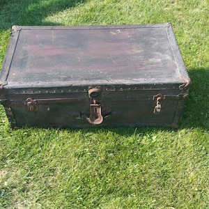 May include: A vintage wooden trunk with a dark brown finish and metal hardware. The trunk has an anchor design on the front and is in good condition.