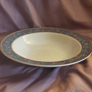Könnte beinhalten: Eine weiße Keramikschüssel mit einem blauen und grünen Blumenmuster am Rand. Die Schüssel hat eine leicht abgerundete Form und ist perfekt zum Servieren von Suppe oder Salat.