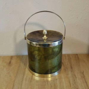 May include: A green and gold ice bucket with a silver handle and a gold pineapple finial on the lid.