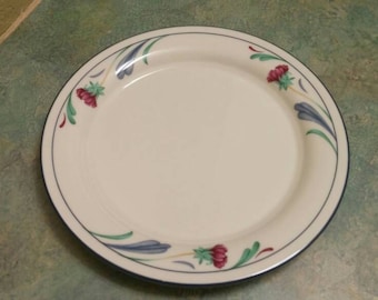 May include: A white ceramic plate with a blue and green floral design. The plate has a scalloped edge and is decorated with red flowers and green leaves.