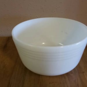 May include: A white ceramic mixing bowl with a smooth, rounded interior and three raised bands around the exterior.