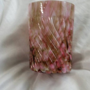 May include: A swirl glass vase with a pink and brown marbled design. The vase is made of glass and has a cylindrical shape.