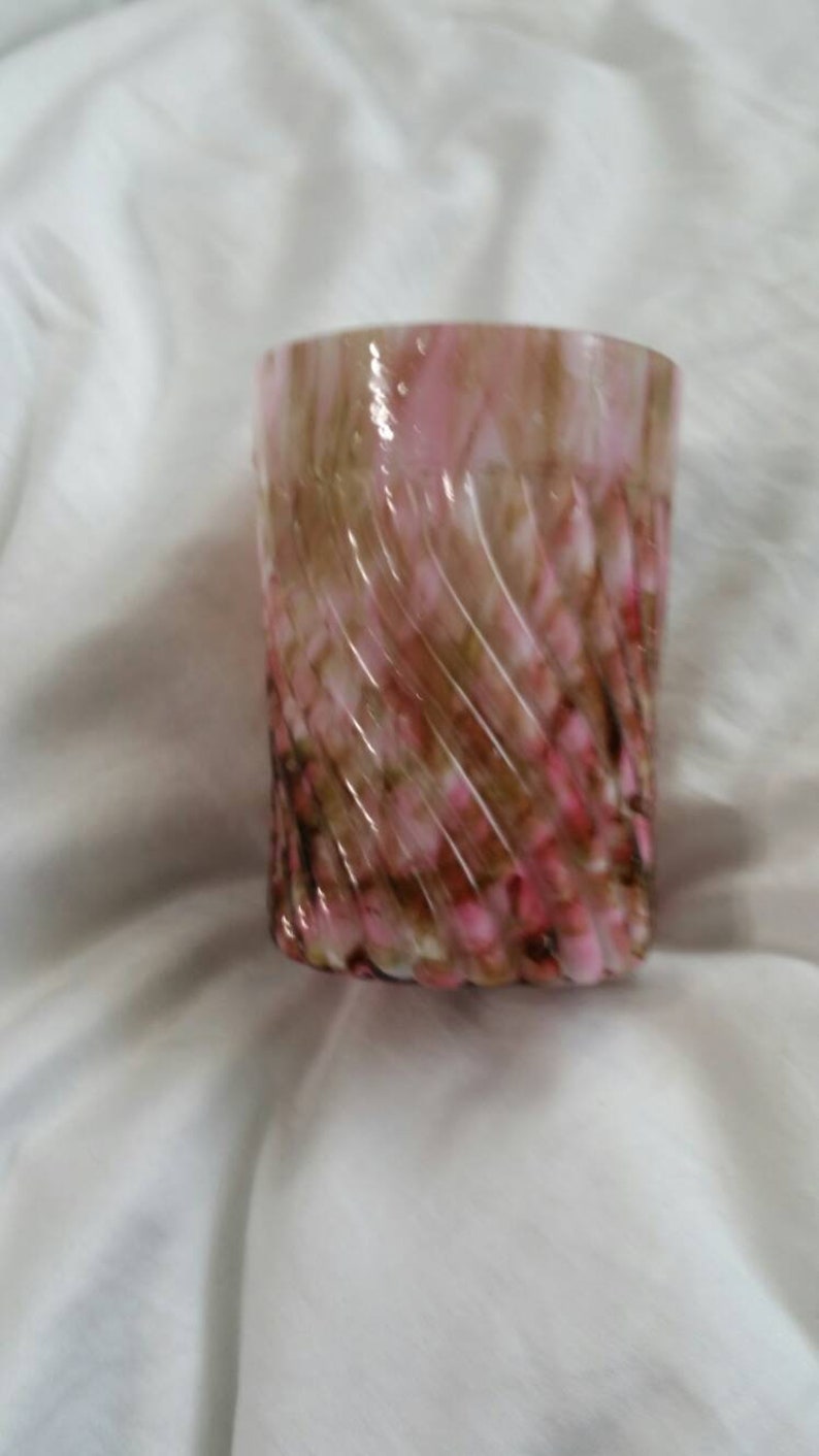 May include: A swirl glass vase with a pink and brown marbled design. The vase is made of glass and has a cylindrical shape.
