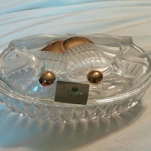 Peut inclure: Un plat en verre transparent avec un motif décoratif floral. Le plat comporte deux accents dorés sur le dessus. Le plat est étiqueté "Silver Nova".