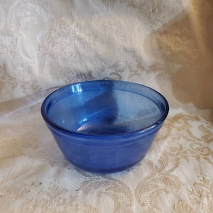 May include: A small, blue glass mixing bowl. The bowl is round and has a smooth, glossy finish.