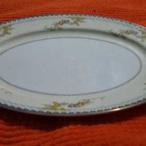 Könnte beinhalten: Eine ovale Servierplatte mit weißem Hintergrund und einem blauen, goldenen und floralen Rand.