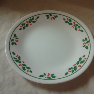 May include: White ceramic plate with a green and red holly design around the rim.