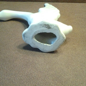 May include: A white ceramic goose figurine in mid-flight, with outstretched wings and a long neck. The underside reveals a hollow base. The sculpture is smooth and appears to be unpainted, with a matte finish.