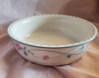 May include: A white ceramic bowl with a blue and green floral design. The bowl has a scalloped edge and a floral pattern with pink roses and blue flowers.