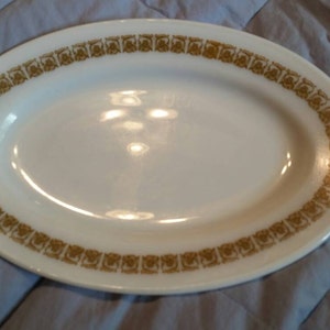 Puede incluir: Plato ovalado blanco para servir con un patrón floral dorado alrededor del borde.