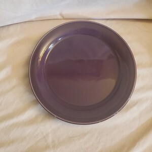 Op de afbeelding: Een grote, ronde, paarse keramische plaat. De plaat is glad en heeft een lichte glans.