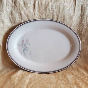 Puede incluir: Plato ovalado blanco para servir con borde dorado y burdeos y un diseño floral en tonos grises y morados.