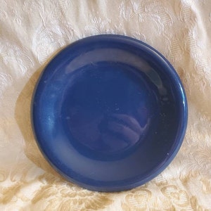 May include: A solid blue ceramic saucer. The saucer is round and has a smooth, glossy finish.