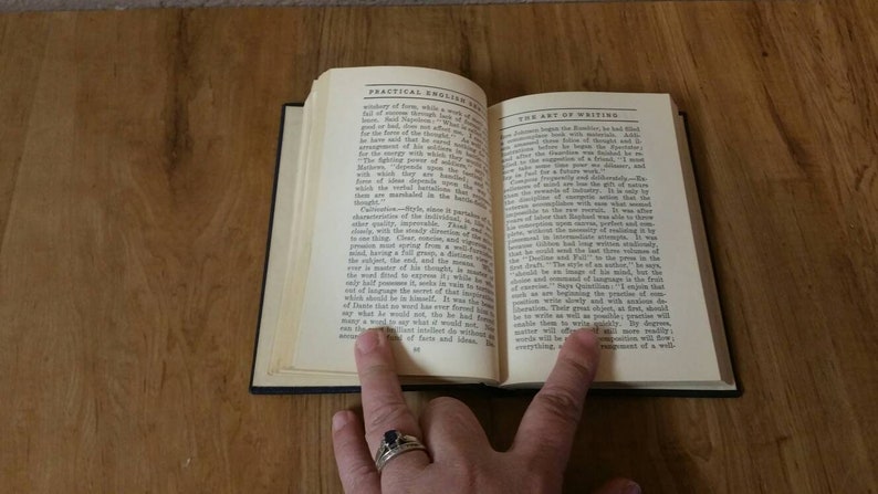 May include: An open book with the title "Practical English Grammar" on the left page and "The Art of Writing" on the right page. The book is open to a page discussing the importance of writing and the use of language.