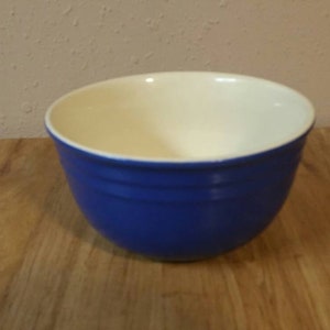 Pode incluir: Uma tigela de mistura de cerâmica azul com interior branco. A tigela tem uma forma arredondada e um acabamento liso e brilhante.