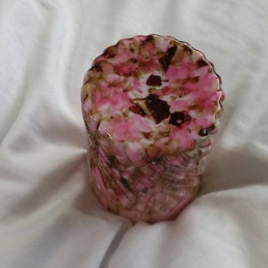 May include: A pink and brown swirl glass vase with a textured surface.