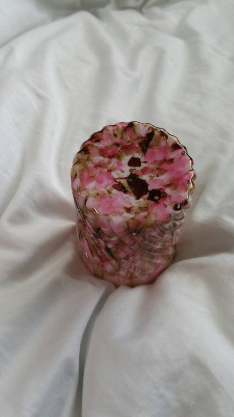 May include: A pink and brown swirl glass vase with a textured surface.