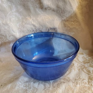 Könnte beinhalten: Eine Kobaltblaue Glasschüssel. Die Schüssel ist rund und hat eine glatte, glänzende Oberfläche.