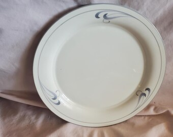 May include: A white ceramic dinner plate with a silver rim and a gray swirl design.