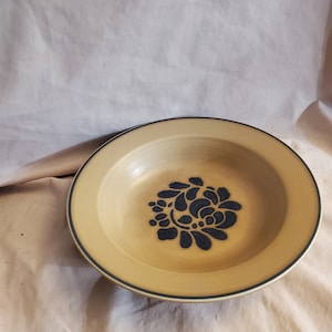 May include: A large, round, beige ceramic bowl with a blue floral design. The bowl has a dark blue rim.