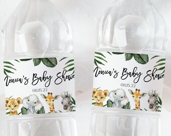 May include: Two clear plastic water bottles with white caps, each featuring a custom label with green tropical leaves and watercolor illustrations of a lion, elephant, giraffe, and zebra. The text reads Tonica's Baby Shower and 08.15.22.