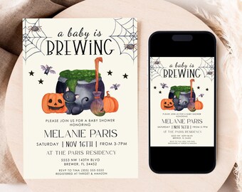May include: A baby shower invitation card and a smartphone displaying the same design. The invitation features the text a baby is BREWING, a black cauldron with green liquid, a black cat, pumpkins, a broom, and spiderwebs on a cream background.
