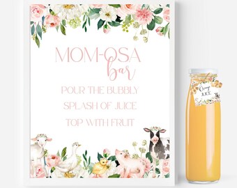 May include: A white framed sign with floral accents and farm animals, featuring the text MOM-OSA BAR, POUR THE BUBBLY, SPLASH OF JUICE, TOP WITH FRUIT. Next to it is a glass bottle filled with orange juice, featuring a tag labeled Orange Juice.
