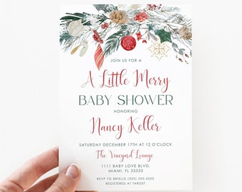 May include: A white baby shower invitation card held by a hand. The card features the text "A Little Merry Baby Shower" in red and green, with festive holiday decorations. The invitation is for Nancy Keller.