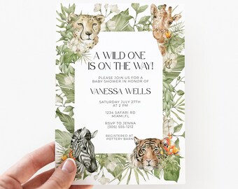 Puede incluir: Una tarjeta de invitación rectangular para baby shower con ilustraciones en acuarela de un guepardo, una jirafa, una cebra y un tigre rodeados de follaje tropical verde. El texto dice: A WILD ONE IS ON THE WAY! PLEASE JOIN US FOR A BABY SHOWER IN HONOR OF VANESSA WELLS.