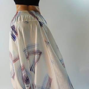 Könnte beinhalten: Weiße Hose mit einem abstrakten Muster in Blau und Rot. Die Hose ist weit geschnitten und hat eine weite Bein.
