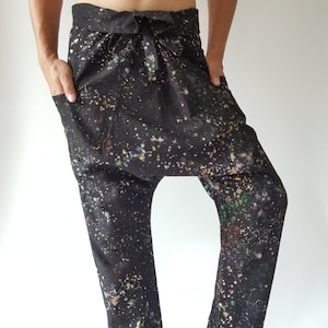 May include: Black trousers with a colourful paint splatter design. The trousers have a drawstring waist and a loose, comfortable fit.