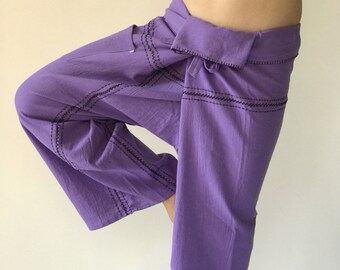 Può includere: Pantaloni in cotone viola con uno stile avvolgente e cuciture decorative. I pantaloni sono legati in vita con una fascia di tessuto.