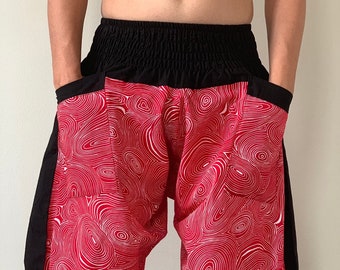 May include: Red and white patterned pants with a black waistband and side panels. The pants feature a unique design of swirling white lines on a red background. The waistband is elasticized. The pants have pockets.