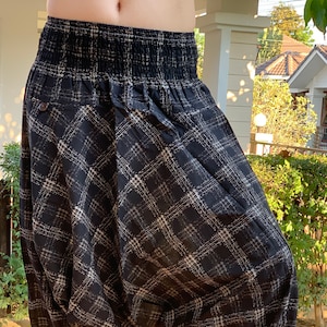May include: Black and white checkered pants with a wide elastic waistband. The pants are gathered at the ankles and have a loose, flowing fit.