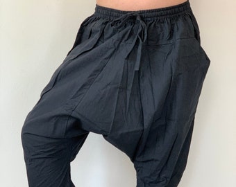 May include: Black, cropped harem pants with a drawstring waist and large pockets. The pants are made of a lightweight fabric and have a relaxed fit. The pants are knee-length and suitable for casual wear.