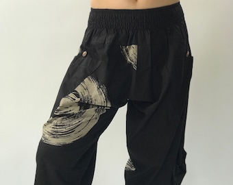 May include: Black pants with a white and gray abstract print. The pants have an elastic waistband and a loose, flowing fit.