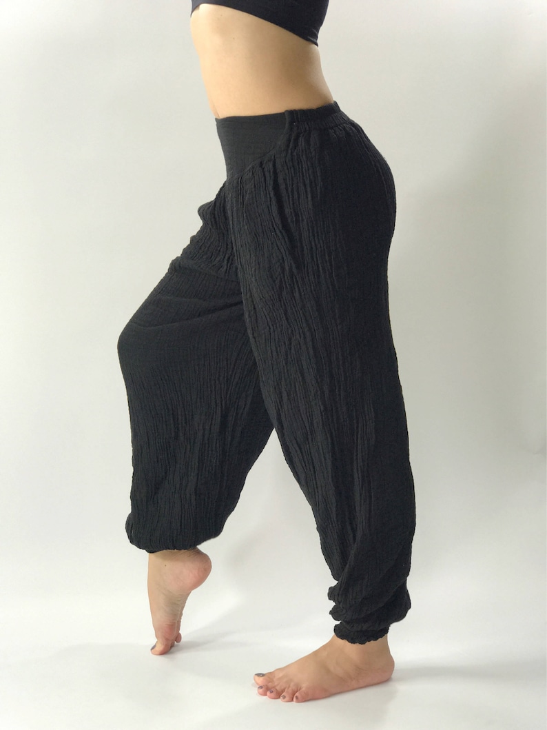 May include: Black, loose-fitting pants with a wide leg and elastic waistband. The pants are made of a soft, crinkled fabric.