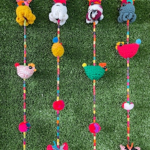 May include: Four colorful crocheted hanging decorations with different animal designs. Each decoration features a beaded string with pom-poms, a bird, and a butterfly.