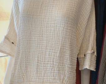 May include: A white, lightweight, textured cotton top with short sleeves and a round neckline. The top has a relaxed fit and is made of a soft, breathable fabric.
