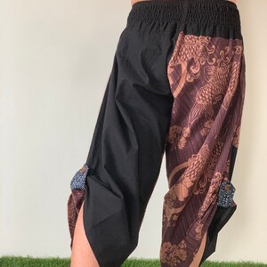 May include: Black and brown pants with a patterned design featuring a fish and floral motifs. The pants have an elastic waistband and a loose fit.