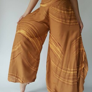 May include: Wide-legged pants with a brown and yellow abstract print. The pants have a loose, flowing fit and a high waist.