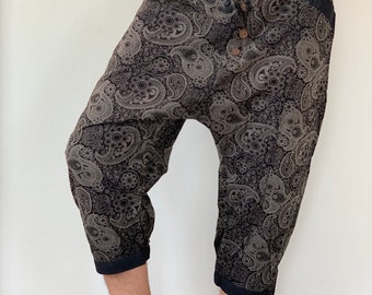 May include: Black and grey paisley print trousers with a drawstring waist and button fastening. The trousers have a loose, comfortable fit and are cropped at the ankle.