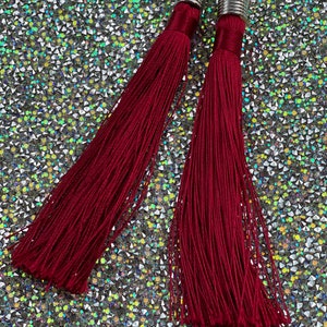 May include: A pair of long, burgundy tassel earrings with silver metal tops.