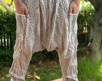 May include: White and black patterned pants with a loose, baggy fit. The pants have a drawstring waistband and pockets on the sides.