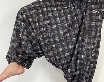 May include: Black and white plaid pants with a drawstring waist. The pants are loose fitting and have a wide leg.