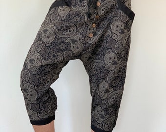 May include: Black and white paisley print trousers with a drawstring waist and button fly. The trousers have a cropped length and are made of a soft, comfortable fabric.
